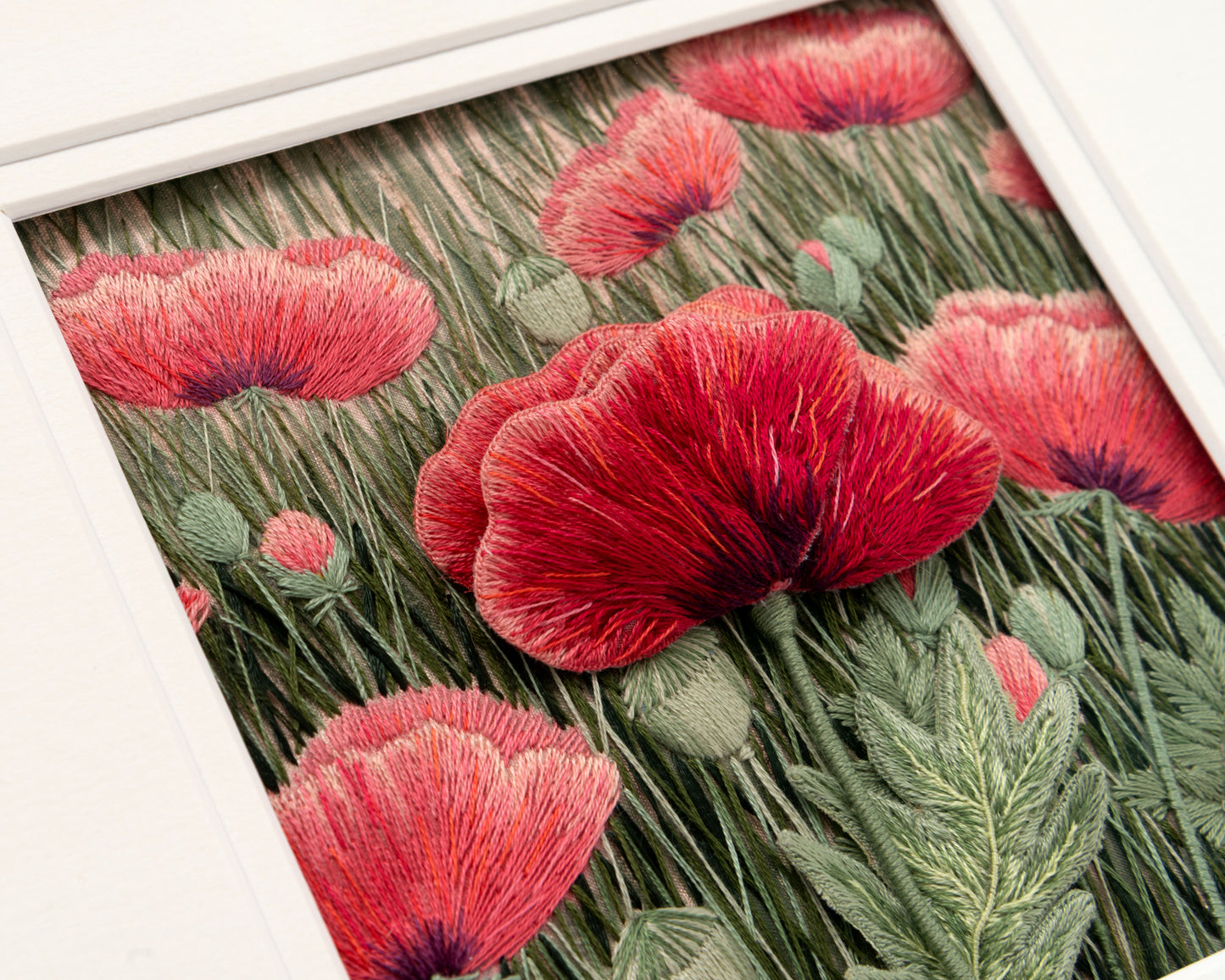 Embroidery stumpwork of red poppies with green leaves on a embroidered background