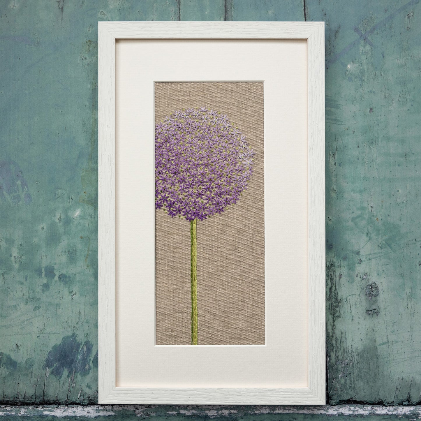 A completed  purple Allium Head hand embroidery kit by Jo Butcher framed with a white frame and mount