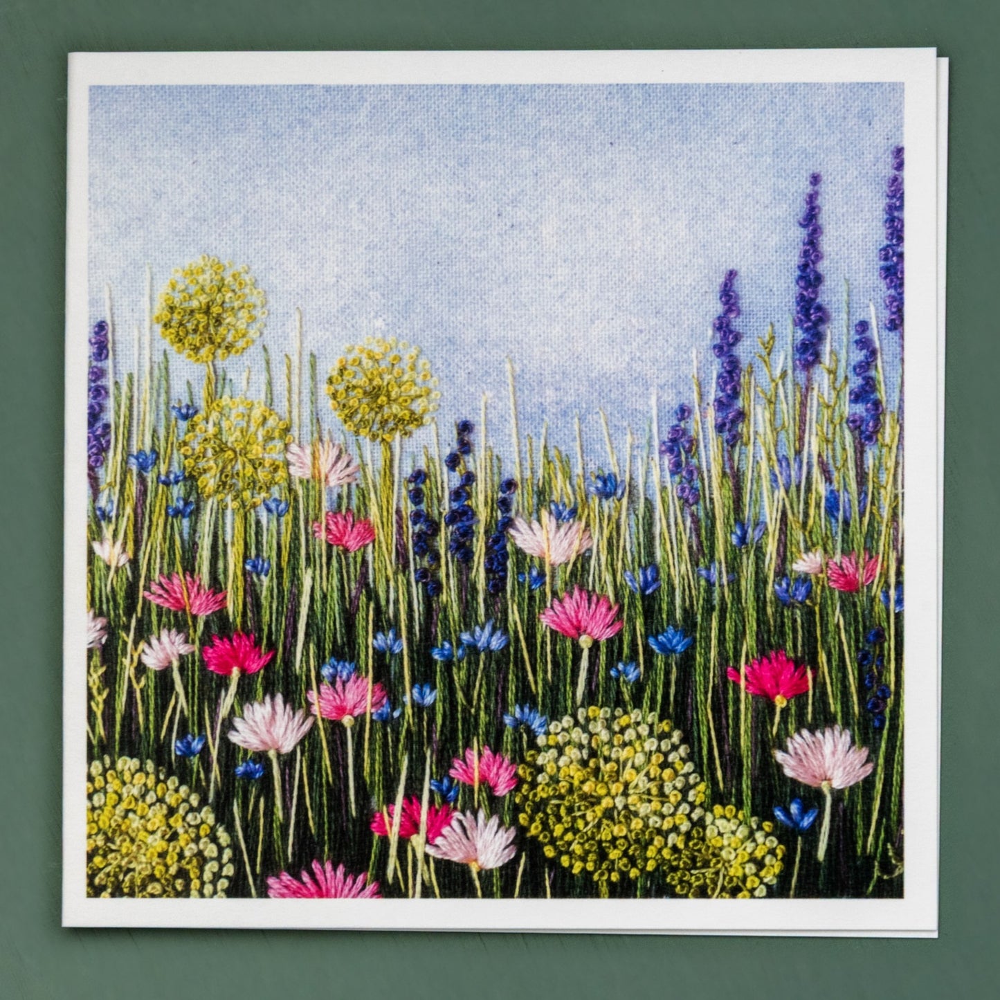 Hand embroidered pale allium heads, salvia spires, pink daisies and pale blue cornflowers sit amongst the grasses.