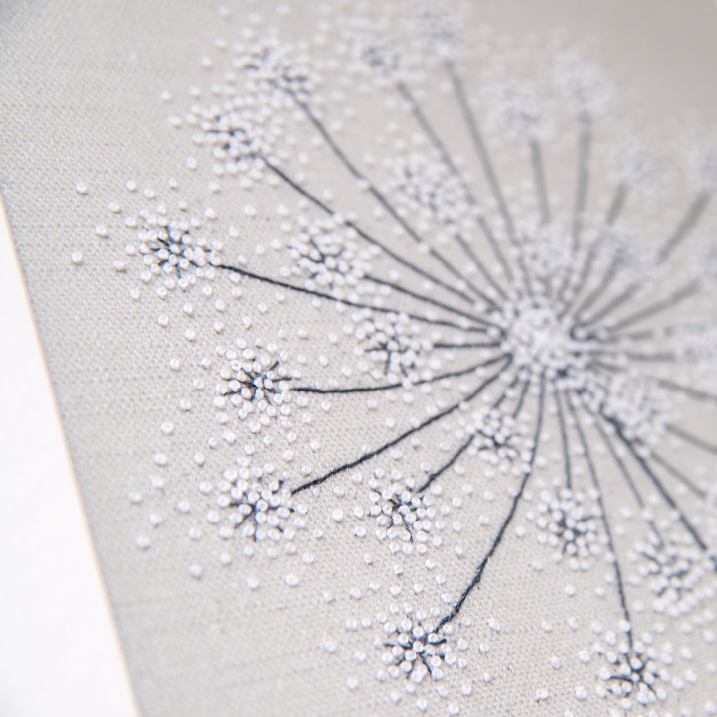 Close up showing the white French knots and dark back stitched stems of this seedhead