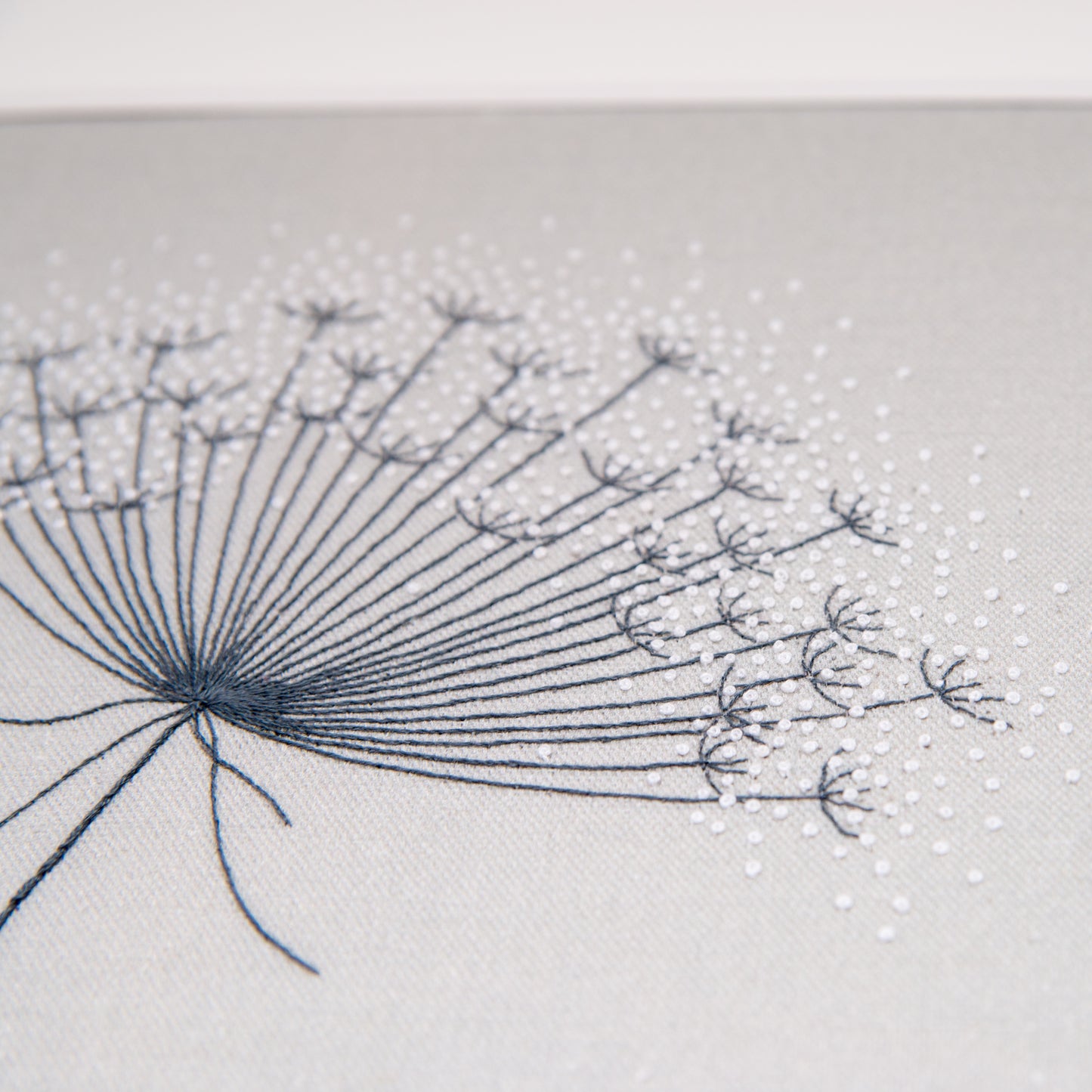 Close up showing the white French knots and dark back stitched stems of this seedhead