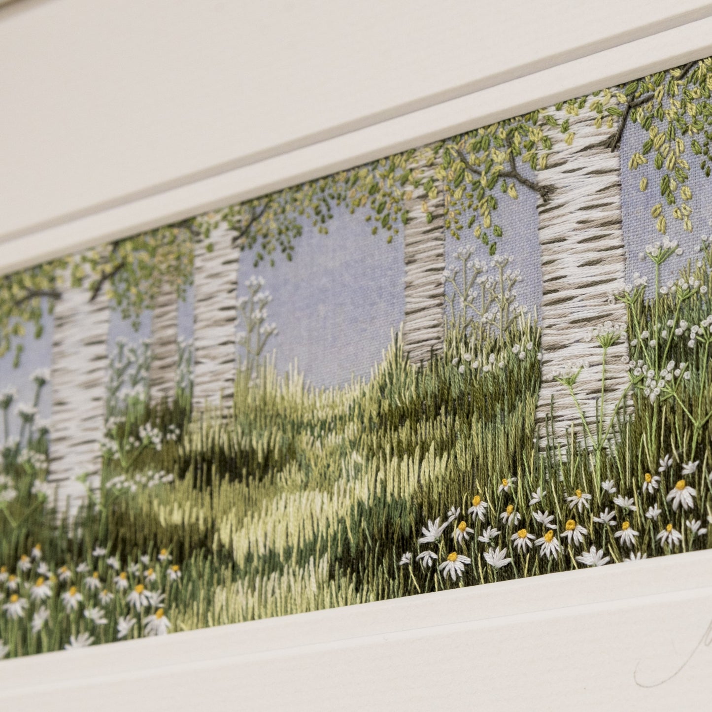 hand embroidered artwork of a glade of silver birch trees with grasses and daises underneath