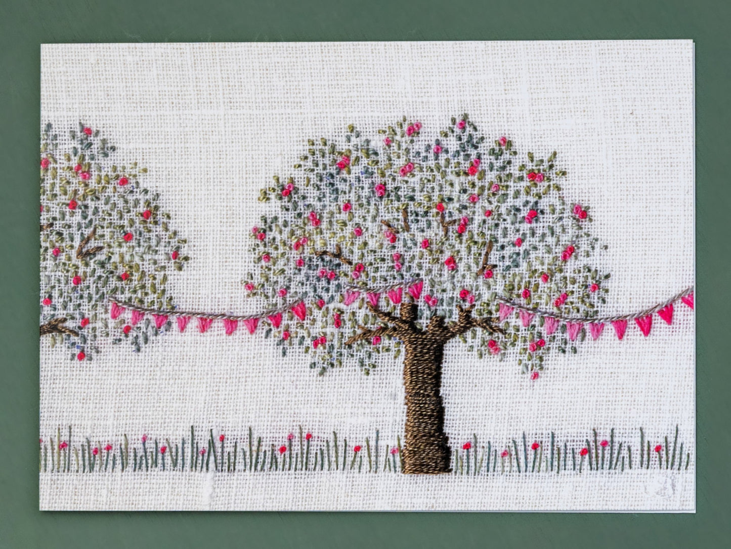 An apple tree with pink Blossom is draped in pretty matching pink bunting.