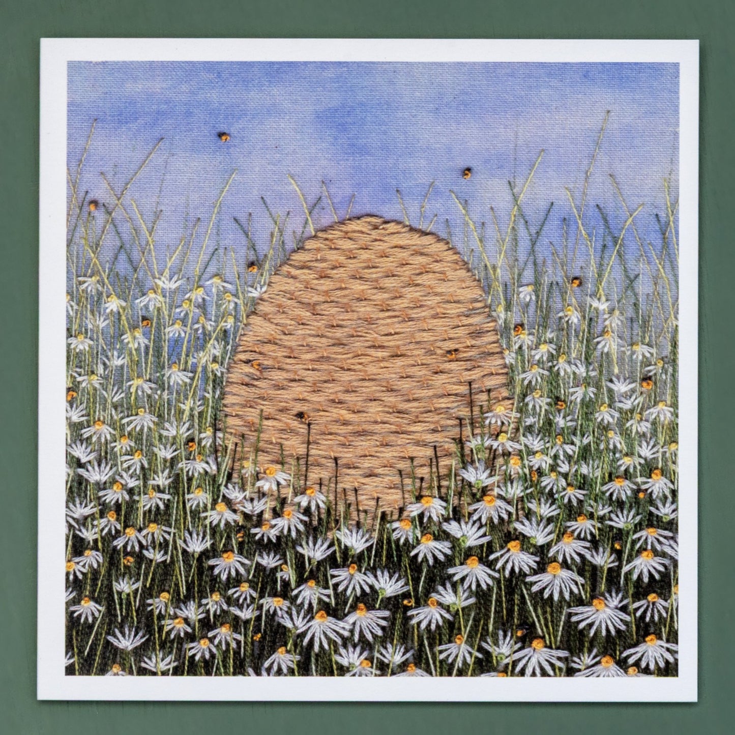 A bee skep sits in a field of daisies.