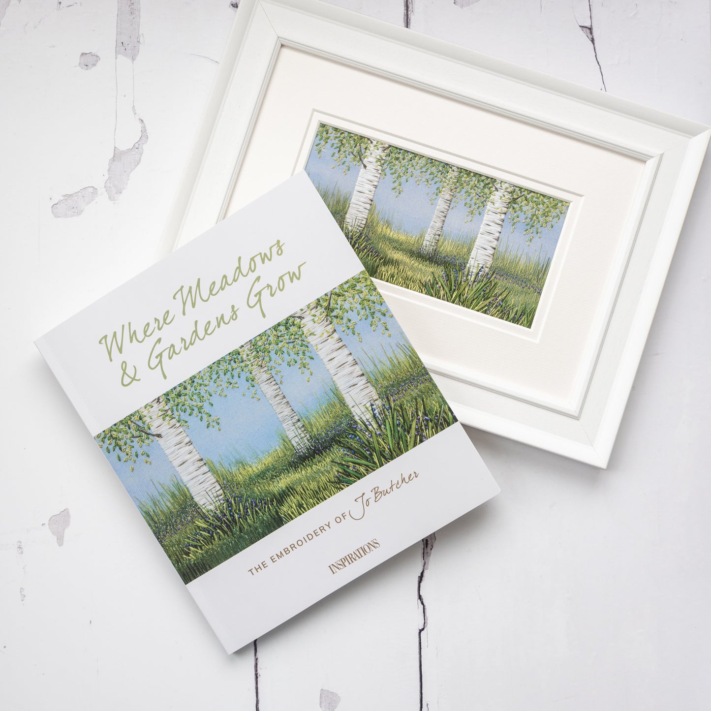 a copy of Jo's book where meadows and gardens grow sits at an angle on the original artwork of bluebells under the birches project that feature in the book and on the cover
