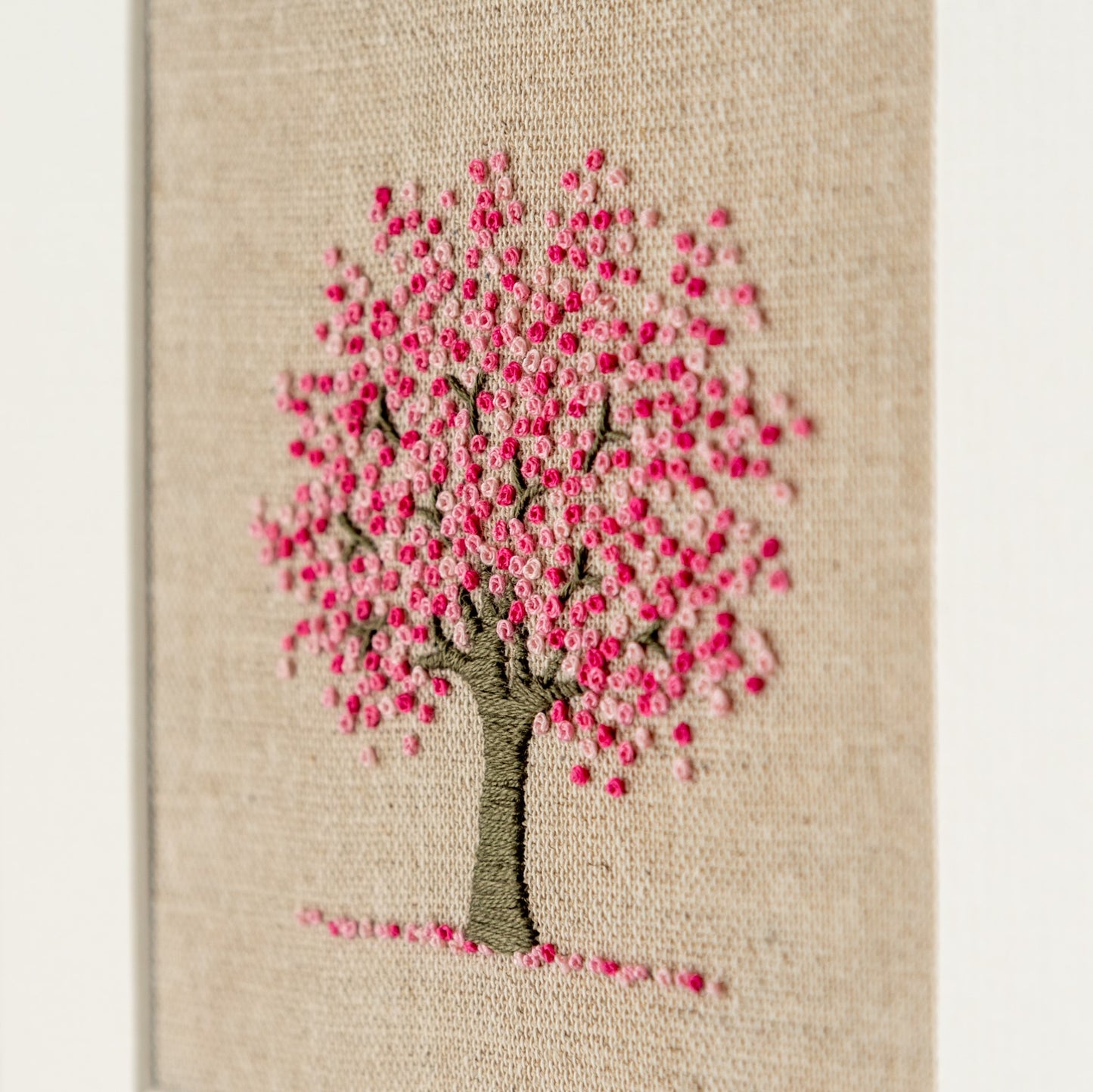 A pretty hand embroidered cherry tree with French knots of various shades of pink representing the blossom.