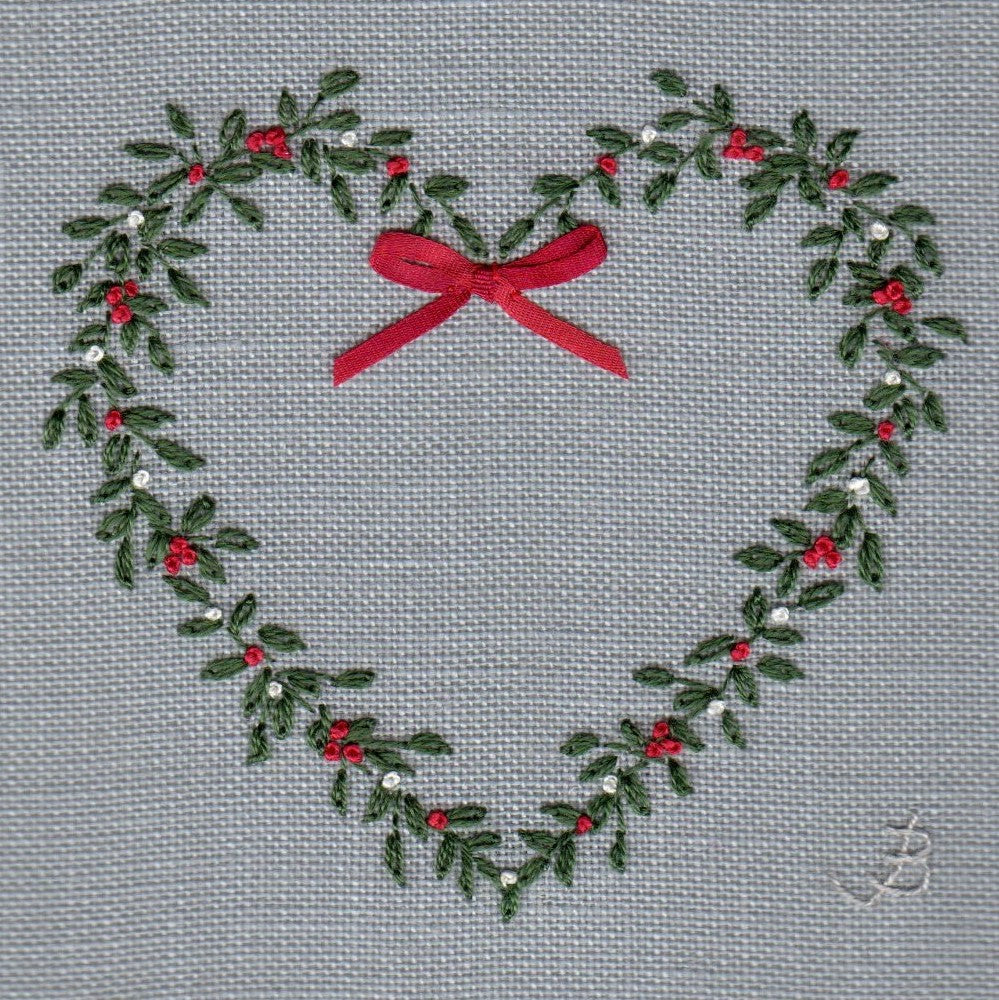 embroidered heart with green leaves and red and white berries. a red ribbon bow is attached to the centre at the top