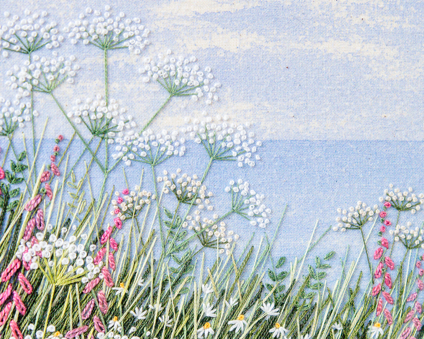 Hand embroidery by Jo Butcher of Cow parsley, daisies and foxgloves in the foreground and the sea and horizon beyond.