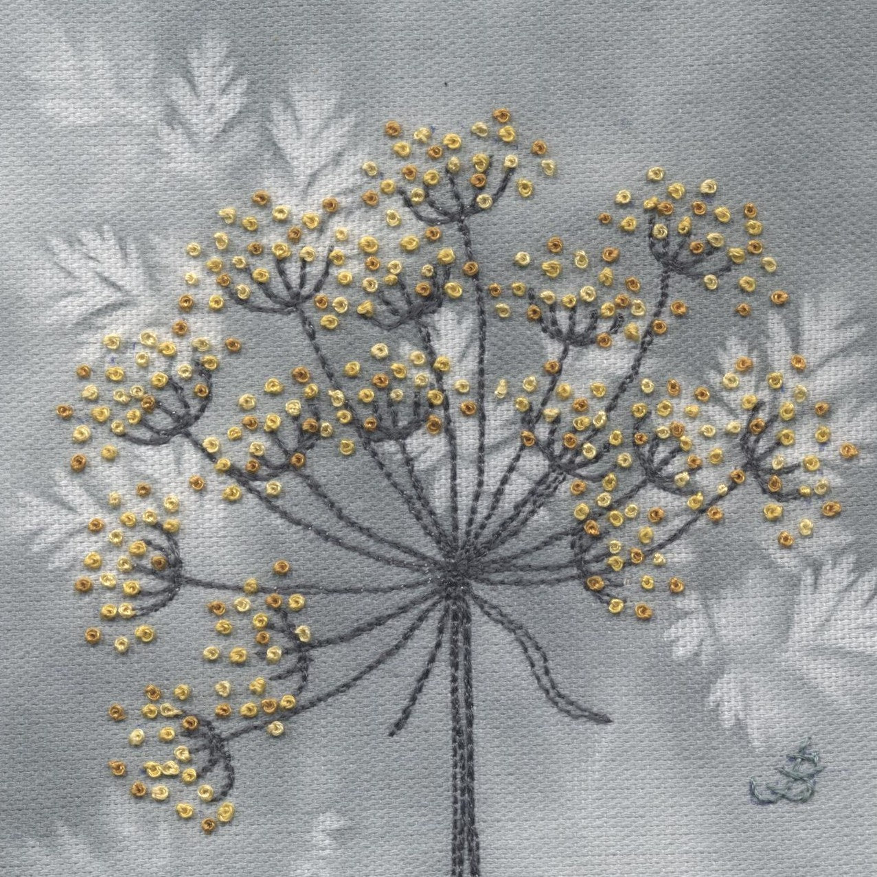 A cow parsley flower flower sewn using yellow French knots with grey/brown stalks on a grey background that has cow parsley leave outlines as a paint effect