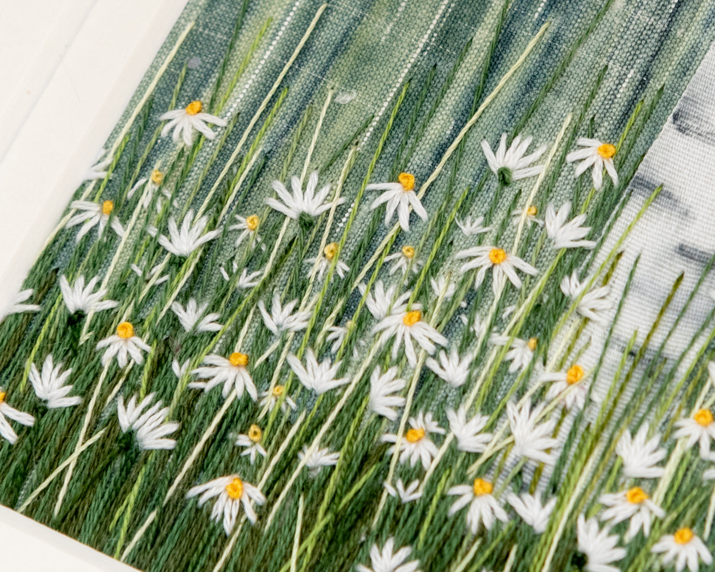 A details view of the hand embroidered white daisies and the birch trunk made from hand painted silk ribbon.