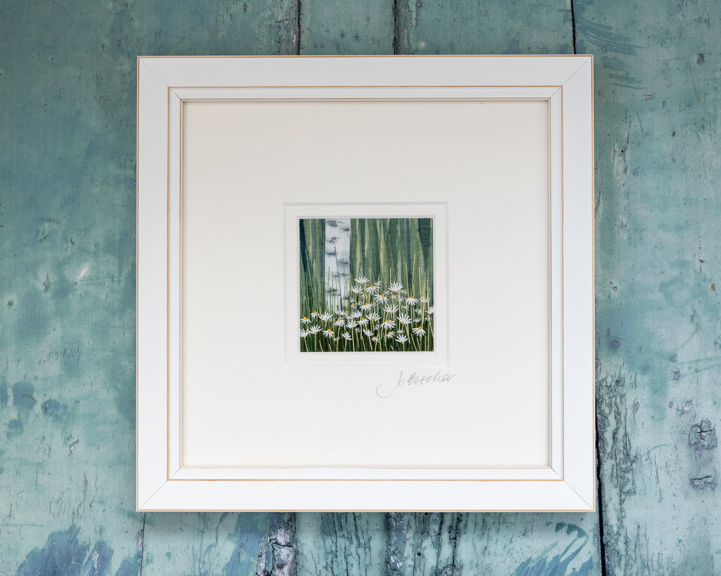 White framed embroidered artwork of a Silver birch rising from a mass of white daises.
