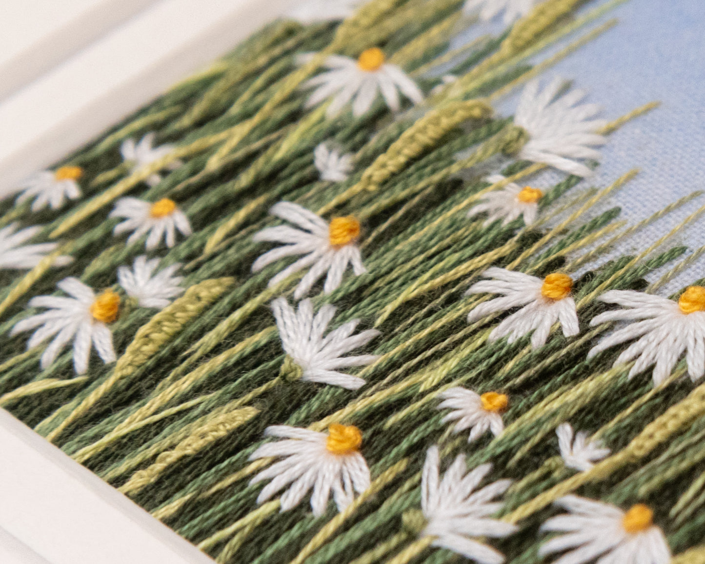 Very close view of the stitches of the daisies and grasses