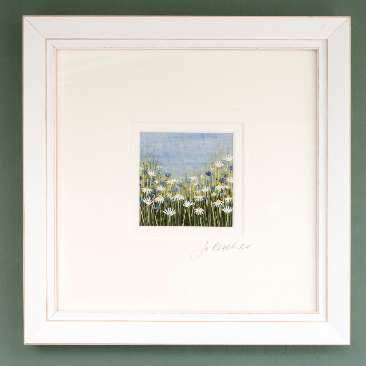white framed artwork of a meadow full of white daisies and classic blue cornflowers.