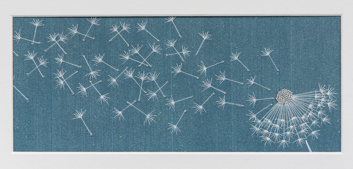 petrol blue background with embroidered dandelion clock dispersing seeds. Stitched with white cotton thread and glass beads