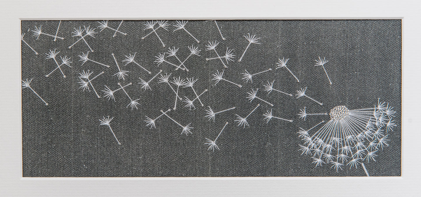 Detailed view of the embroidered dandelion seeds drifting to the left from the clock.