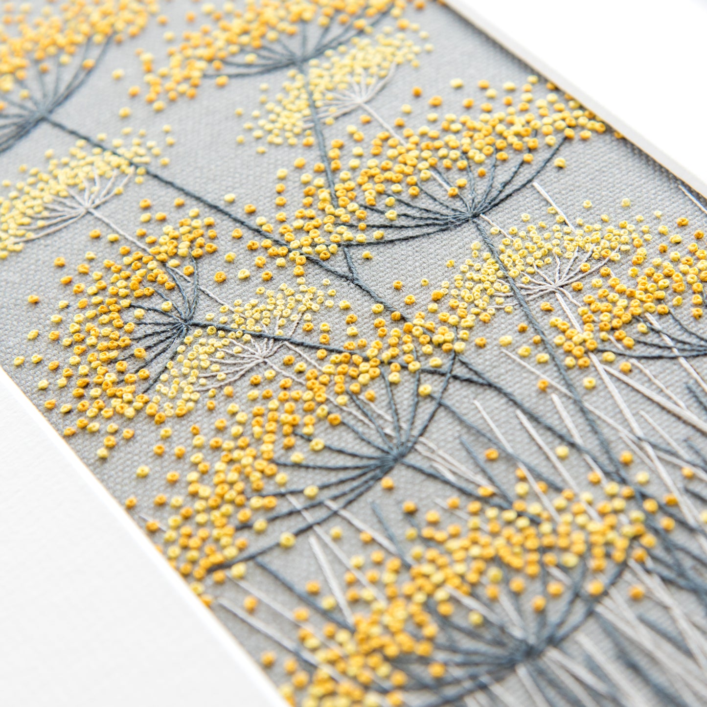embroidered yellow fennel seed heads on a grey linen background