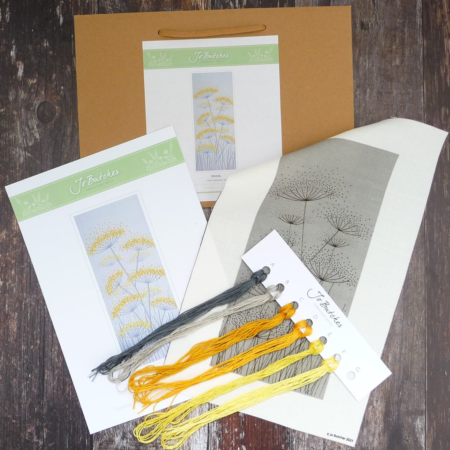 contents of the kit are background fabric with design printed on, threads, and instruction sheet with picture of finished kit on the front.