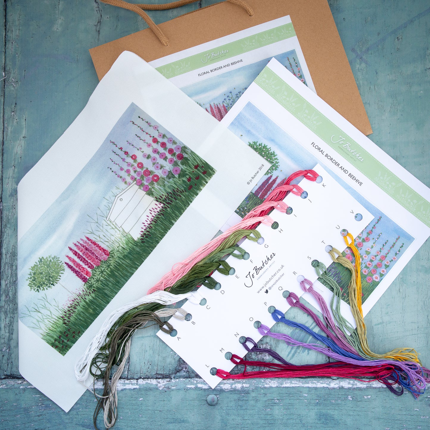 The kit contents are: a printed background, threads, needles and step by step instructions with large picture.