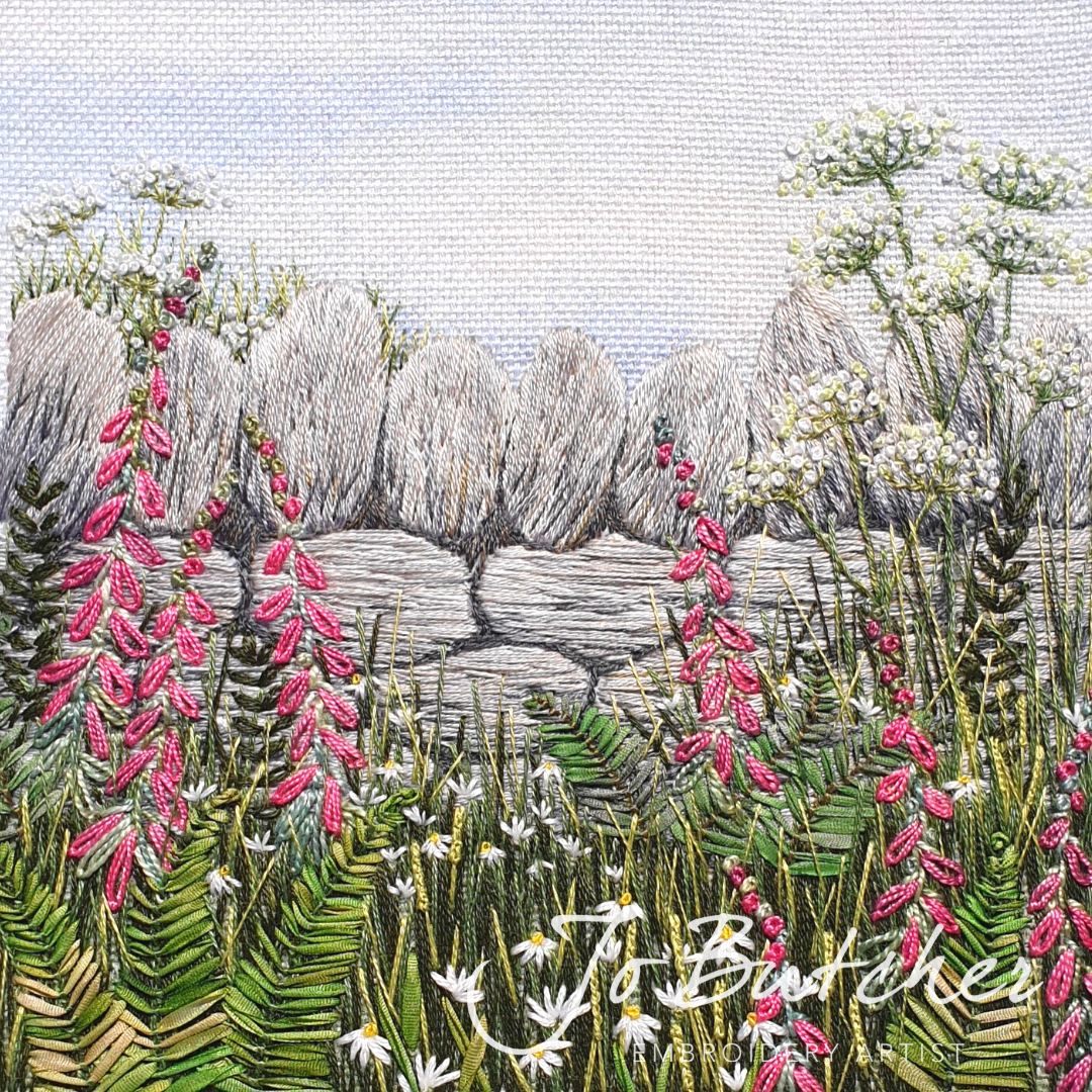 hand embroidered artwork of a dry stone wall with pink foxgloves and ferns growing in front