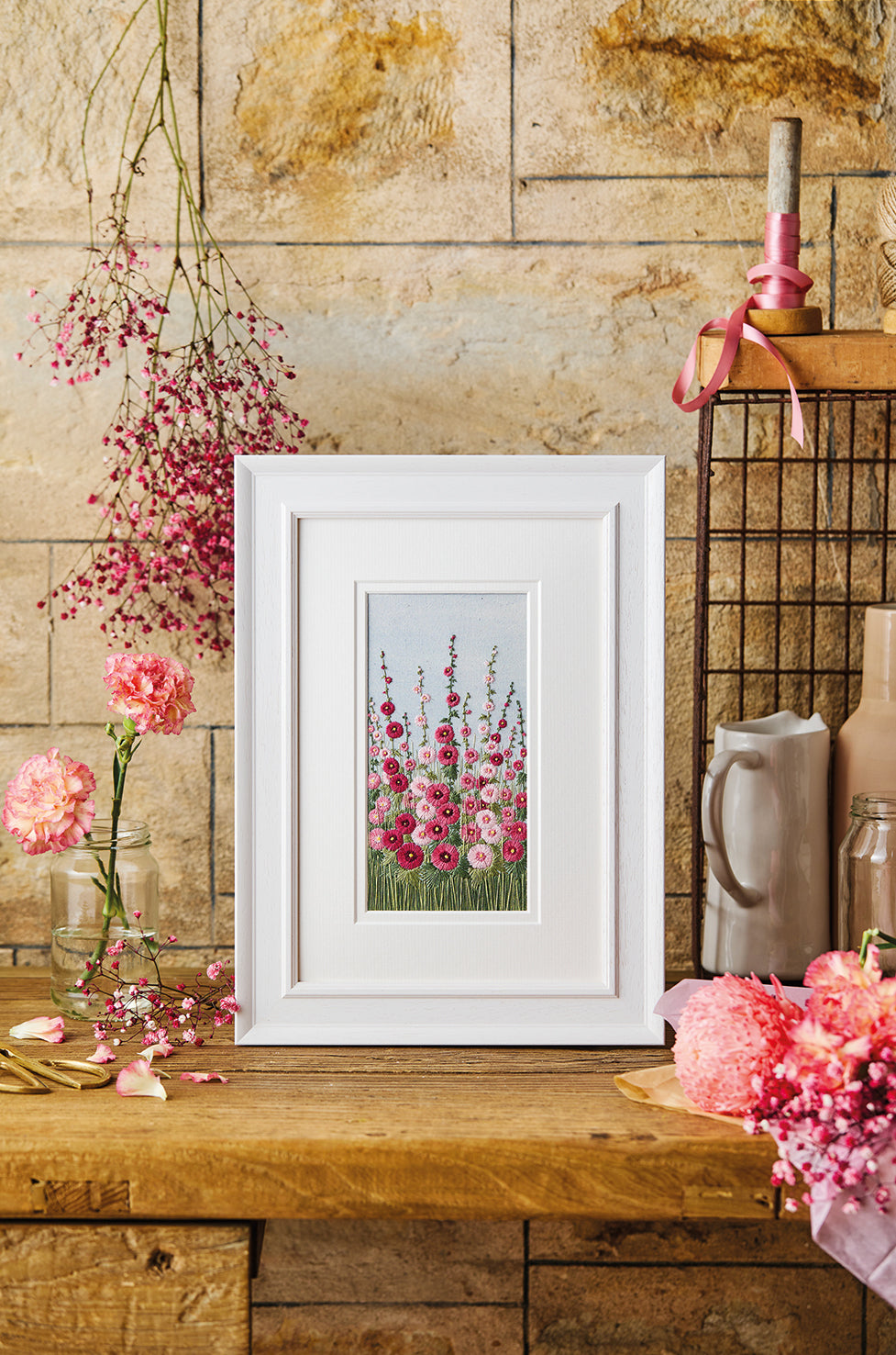 Artwork of pink hollyhocks staged on old wooden dresser