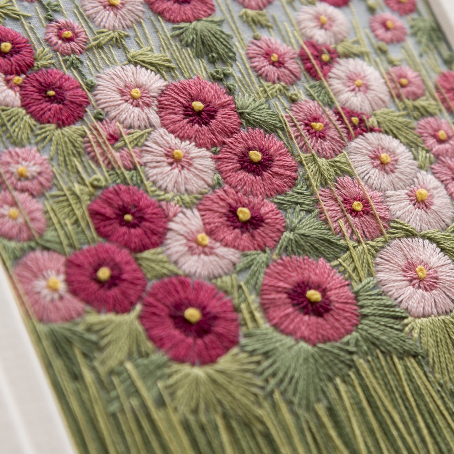 zoomed in image of pink hand embroidered hollyhocks in pink shades