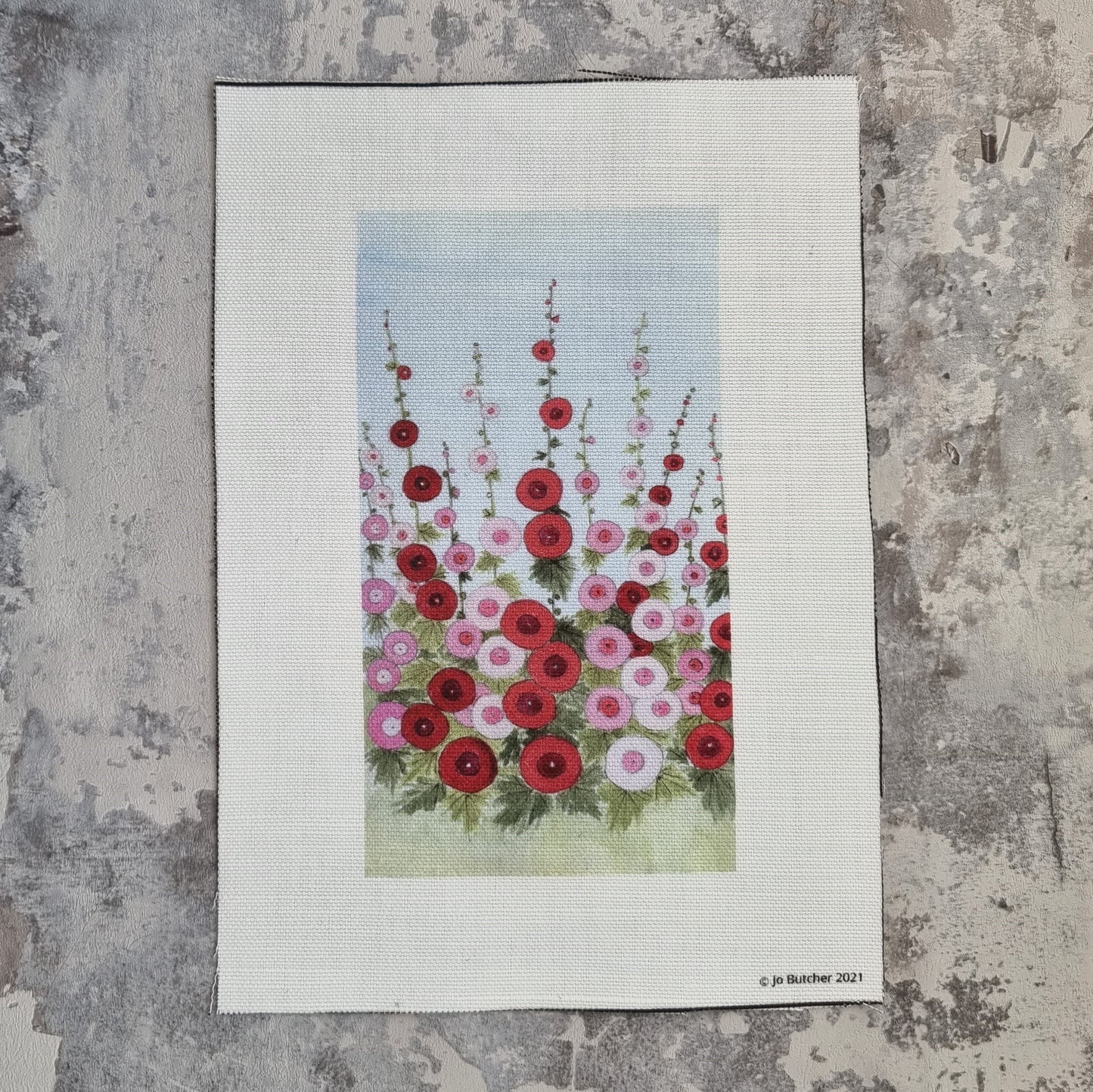 A rectangle of cotton linen with a variety of pink and red Hollyhocks  and foliage.