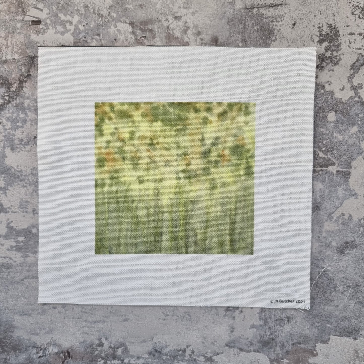 a square of cotton linen with dappled painted background in green and yellow