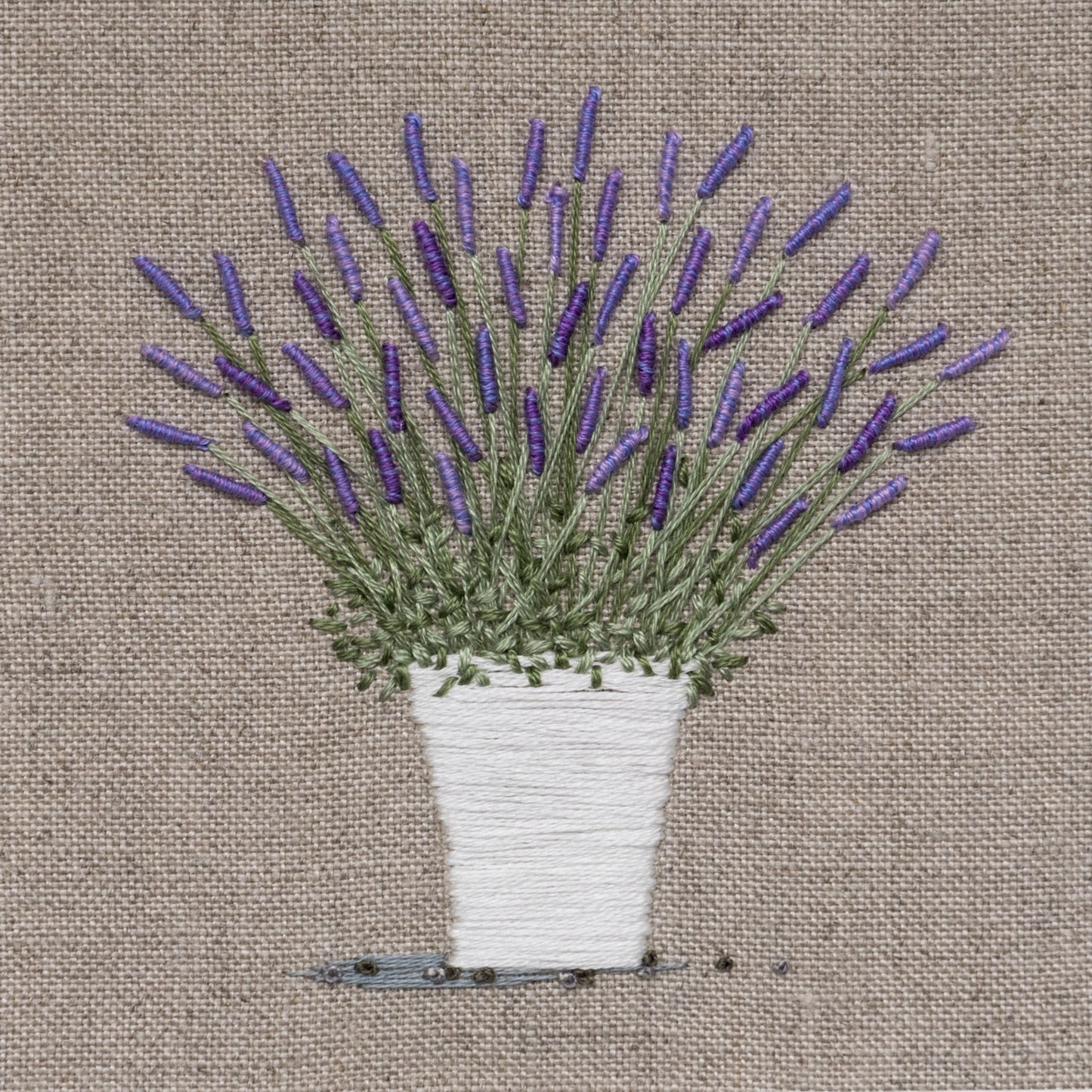 Flowering Lavender in a stitched white pot on a cotton/linen background
