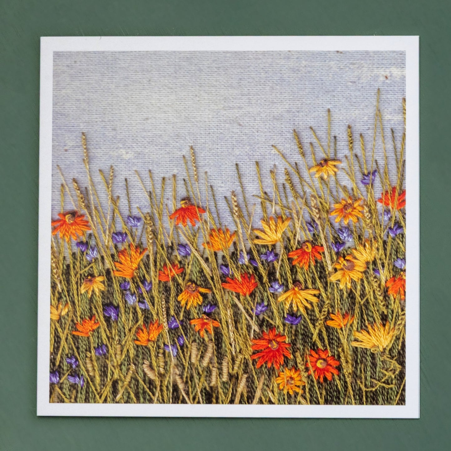 A bright hot orange hand embroidered daisy and grass meadow.