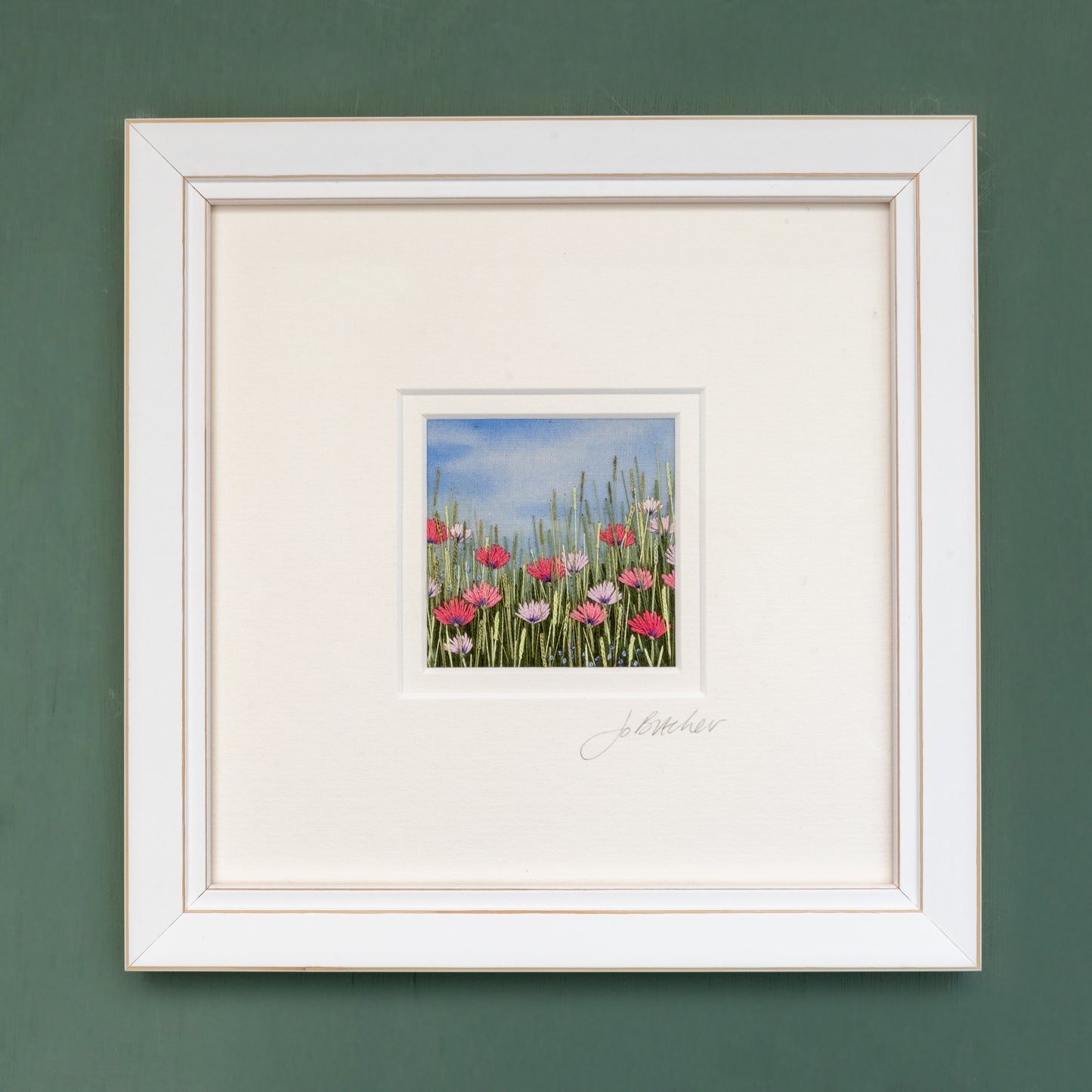 White framed embroidery of a Rabbit's eye view of a pink flower meadow.