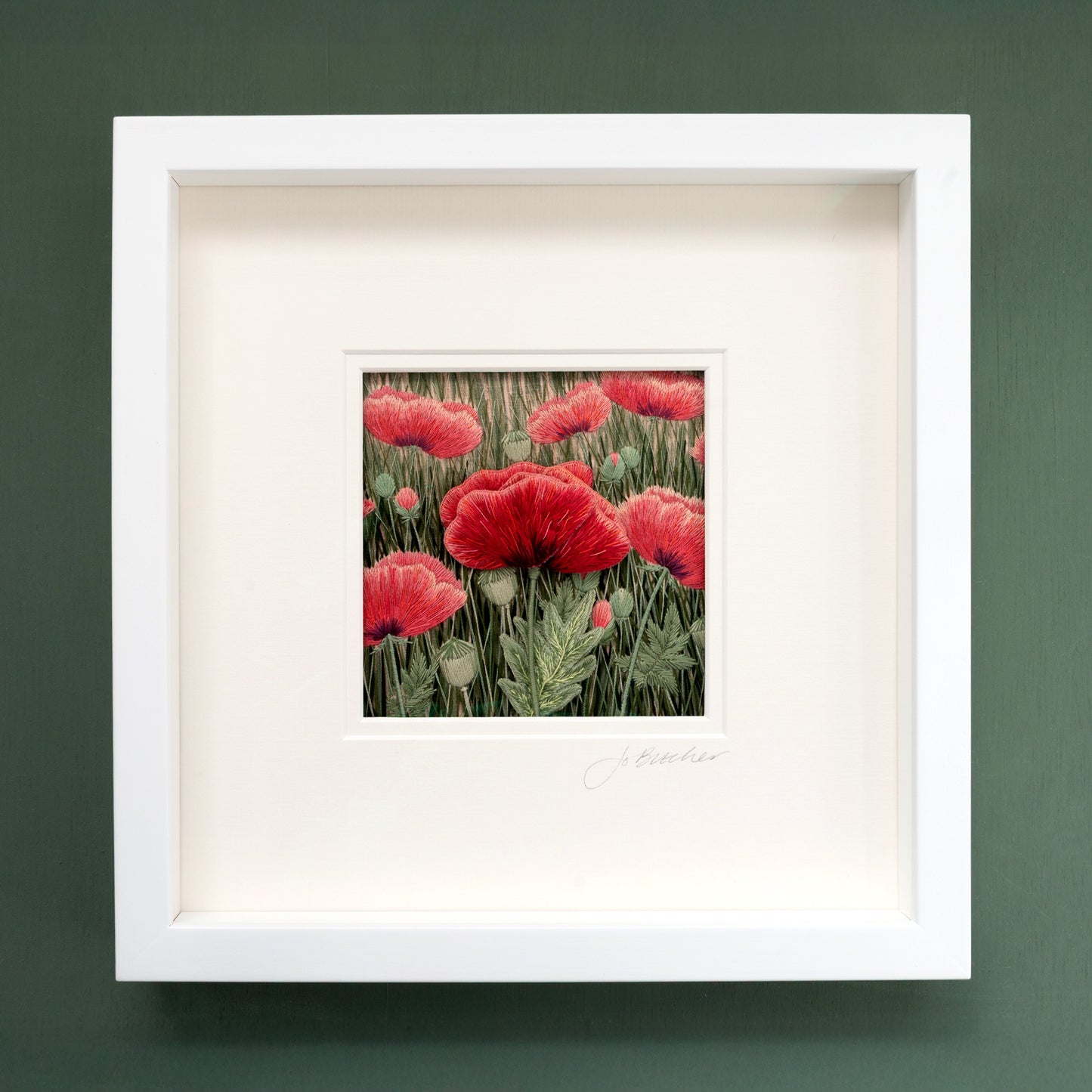 Framed artwork of red poppies on a green background