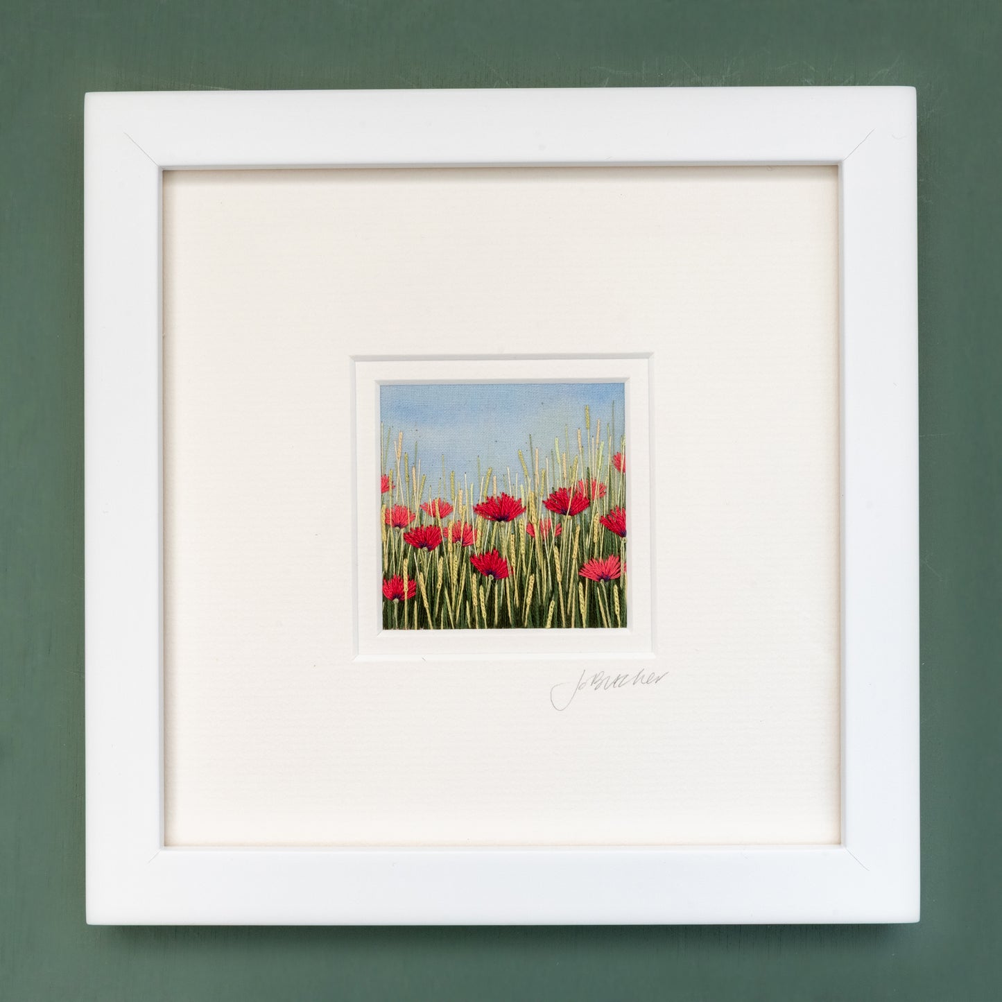 White framed artwork of poppies flowering amongst the grasses
