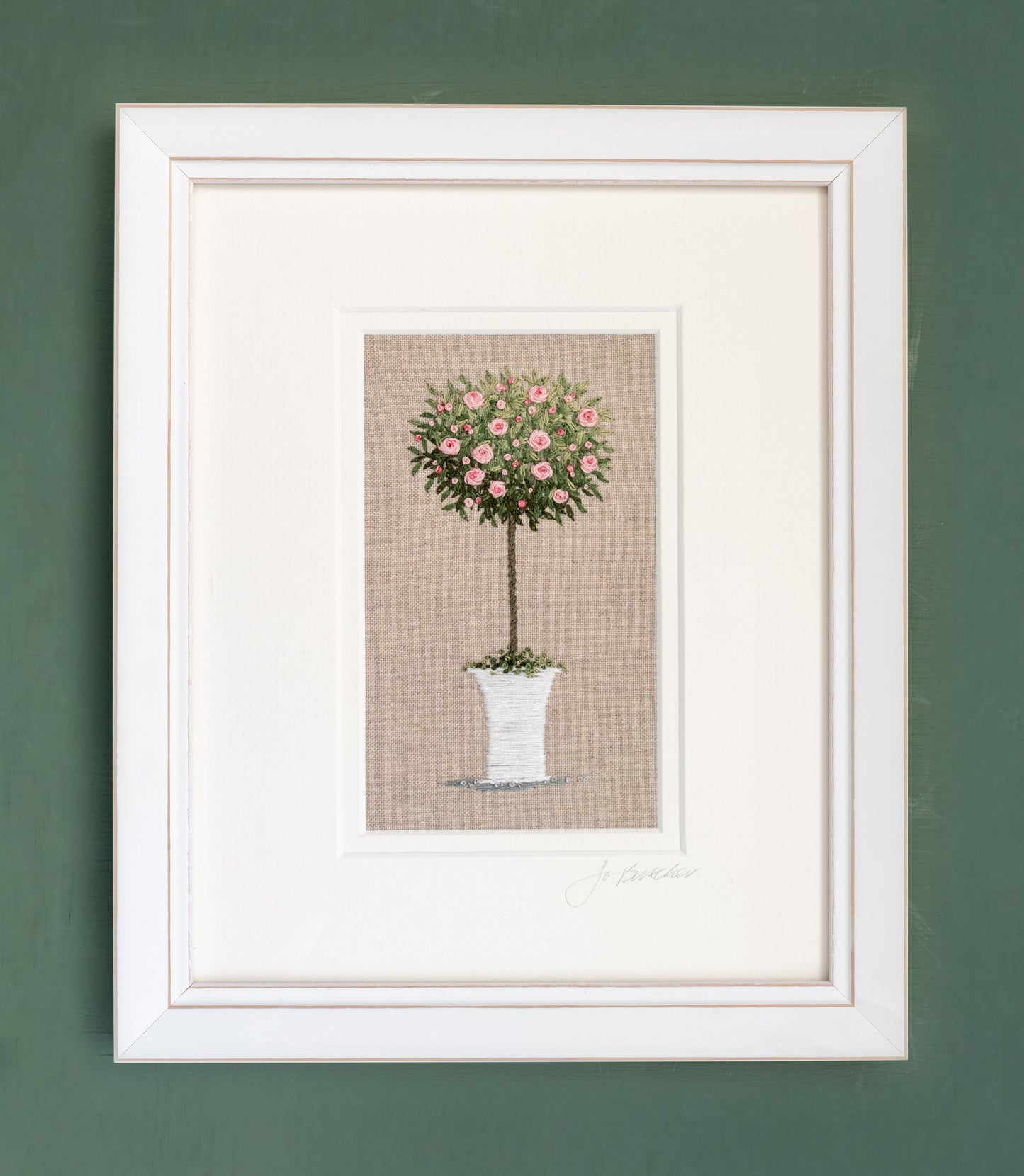 A white framed pink rose tree in a white flower pot embroidered on a beige linen background.