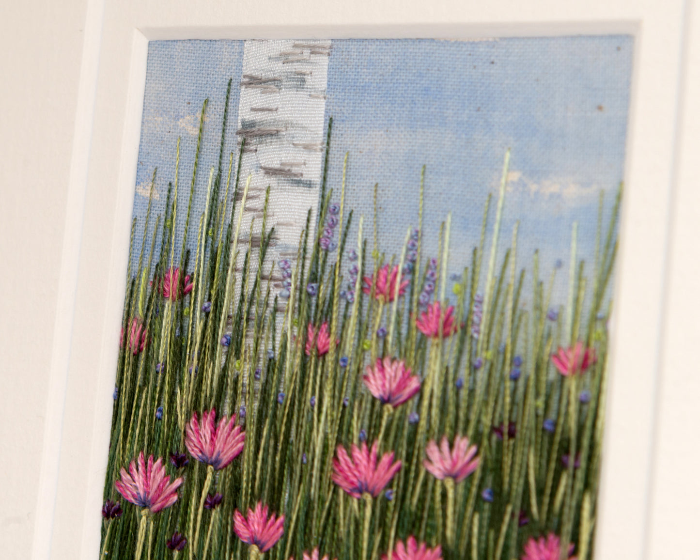 Close up view of the stitch detail of the tree, grass and flowers.