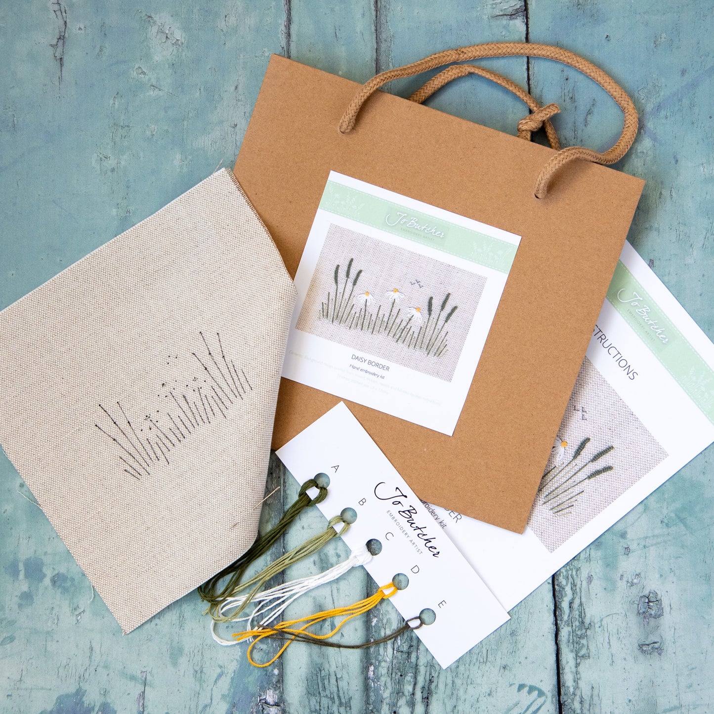 brown paper bag contents include a printed background, threads picture with instructions on the reverse.