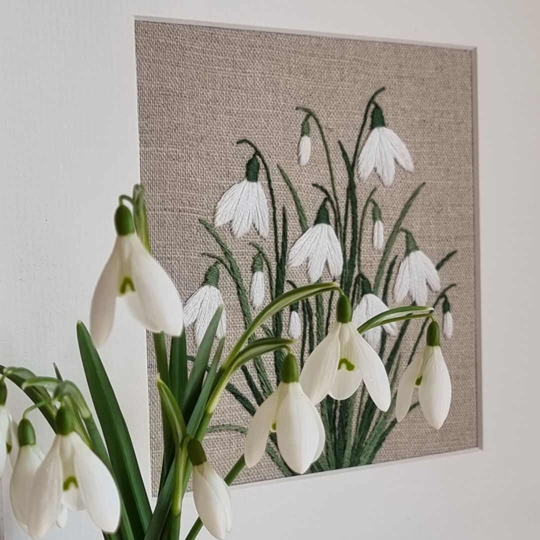 clump of real snowdrops sits in front of hand embroidered snowdrops by Jo Butcher