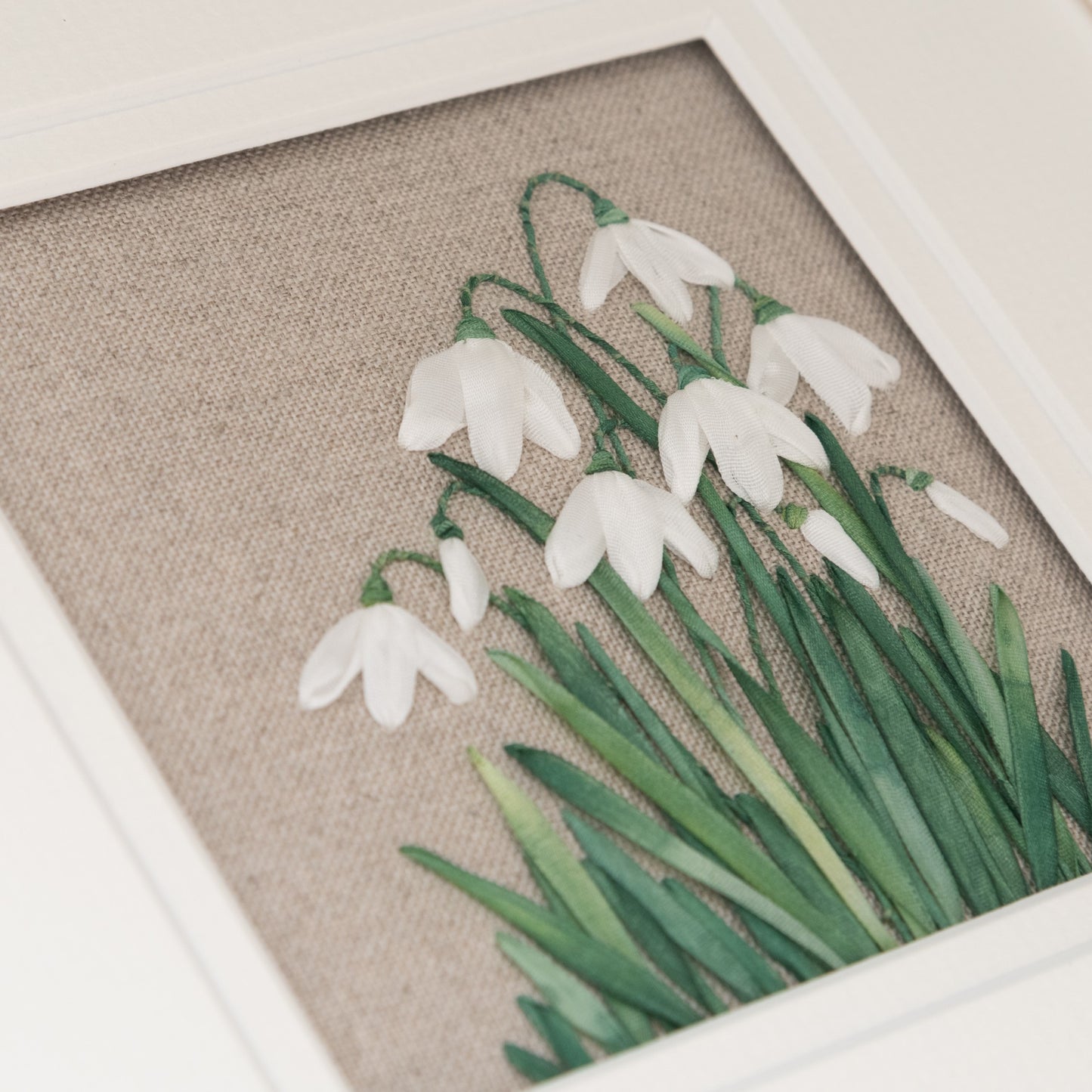 Hand embroidery of a clump of snowdrops in flower and in bud. Embroidered using hand dyed silk ribbons