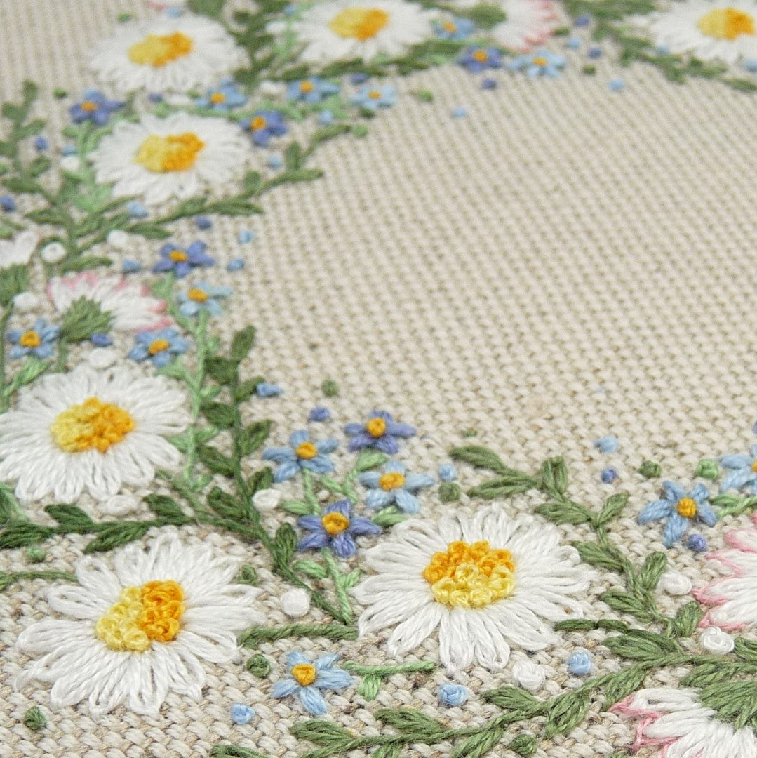 A close up view of the stitching details of this pretty wreath of white daises and   pale blue forget-me-nots.