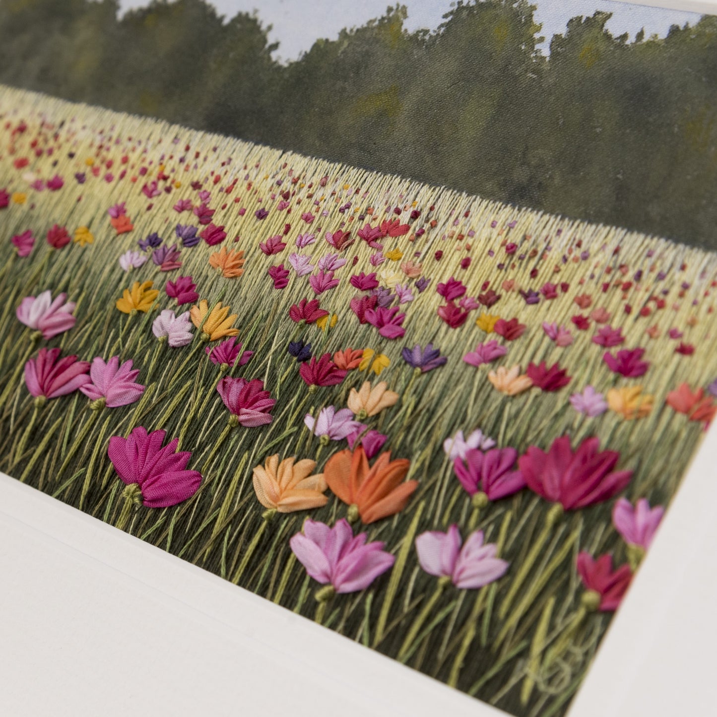 Embroidered field of colourful flowers with a hand painted hedge in the background.