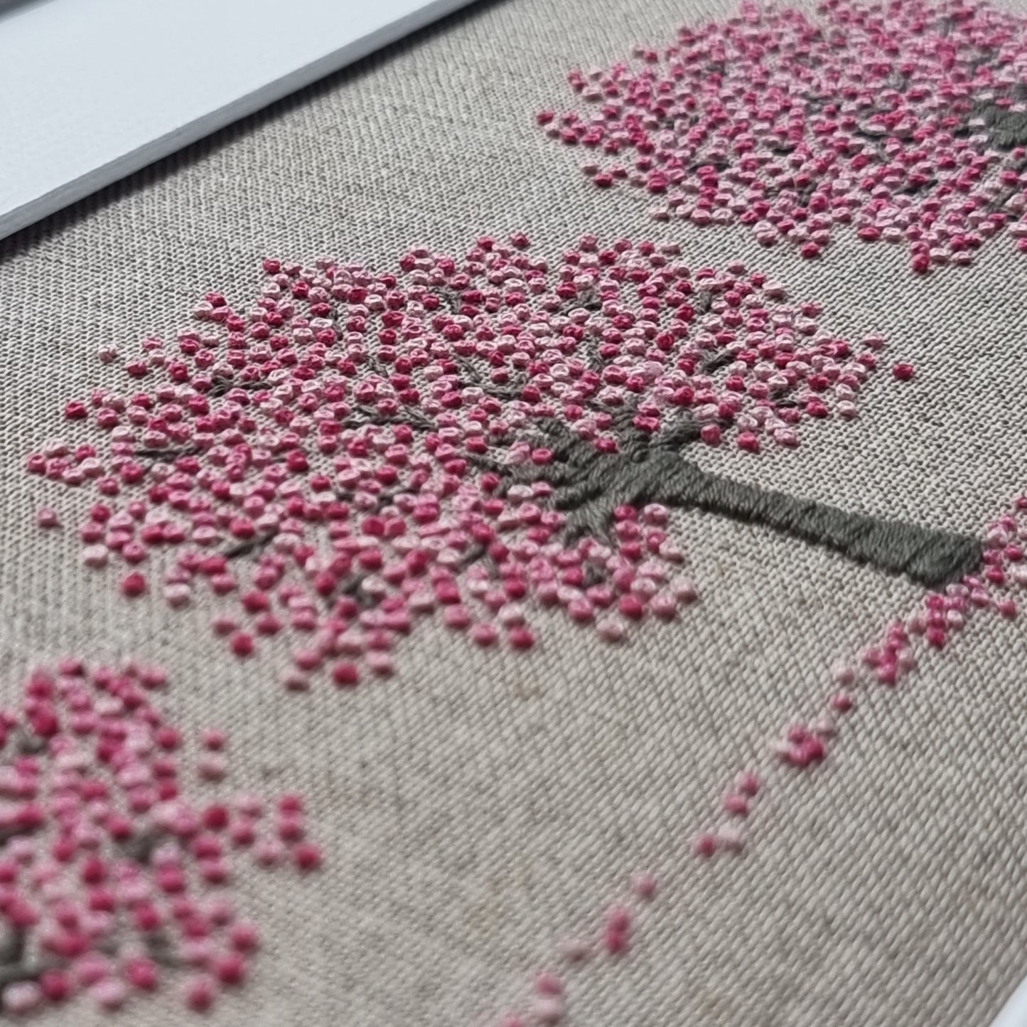 close up of the French knots in various shades of pink that represent the three cherry trees in blossom