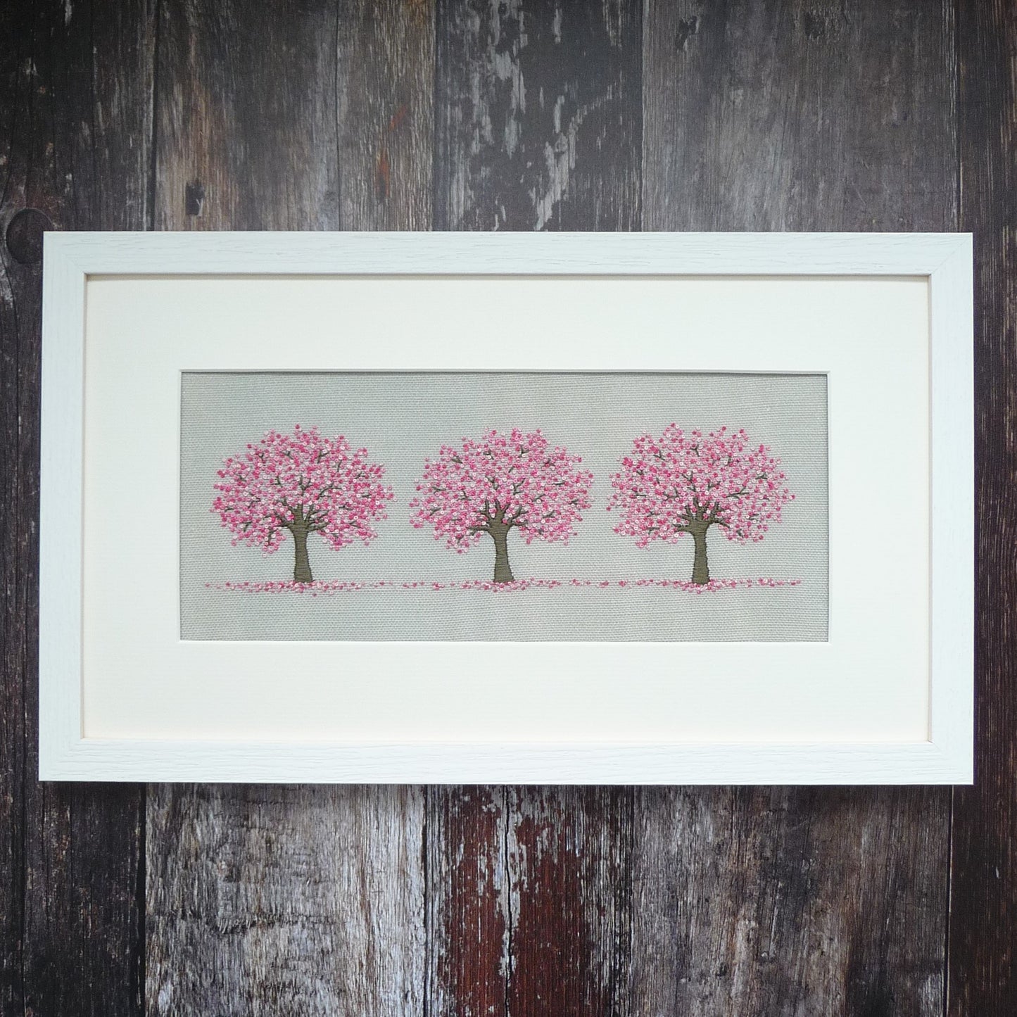 Three pink cherry blossom trees framed  in a white wooden frame