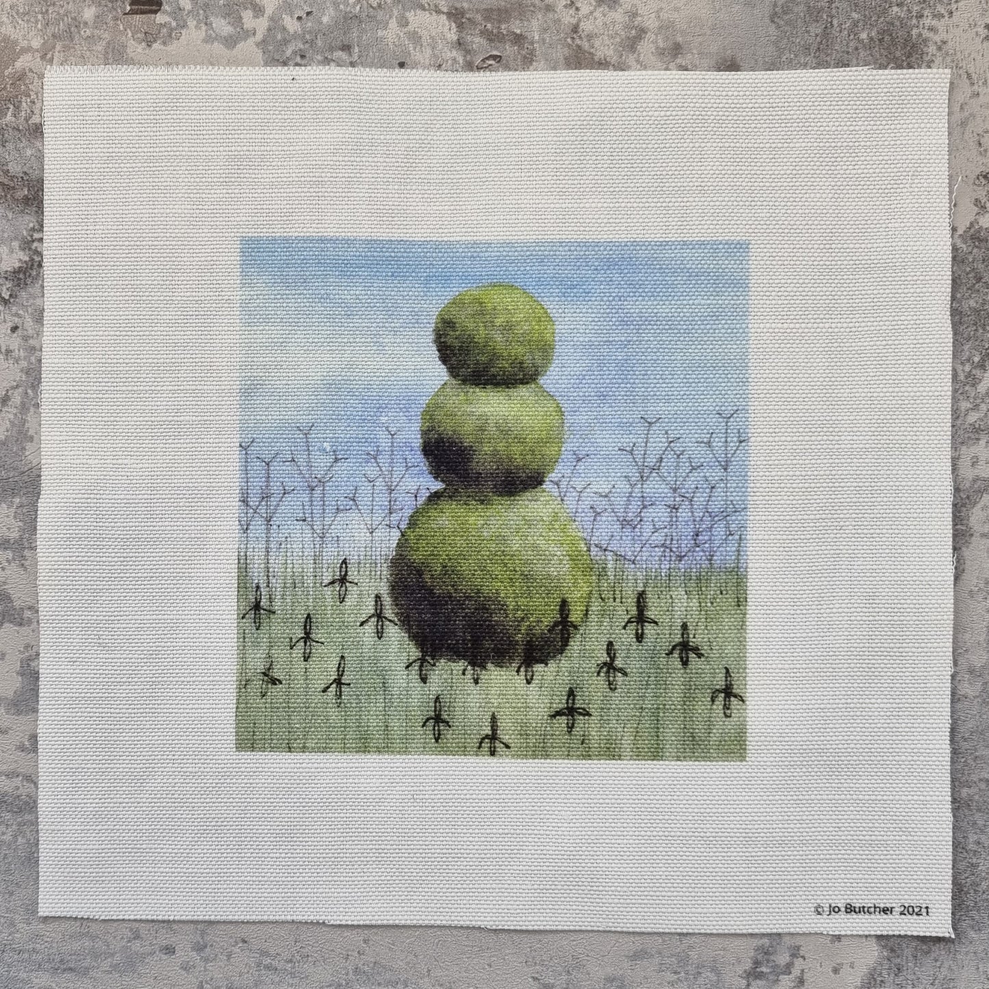 A cotton/linen square which has the outline of three topiary balls on top of each other. The topiary sits in a bed of grasses and the outline of irises and tall verbena are printed for placement and sewing over.
