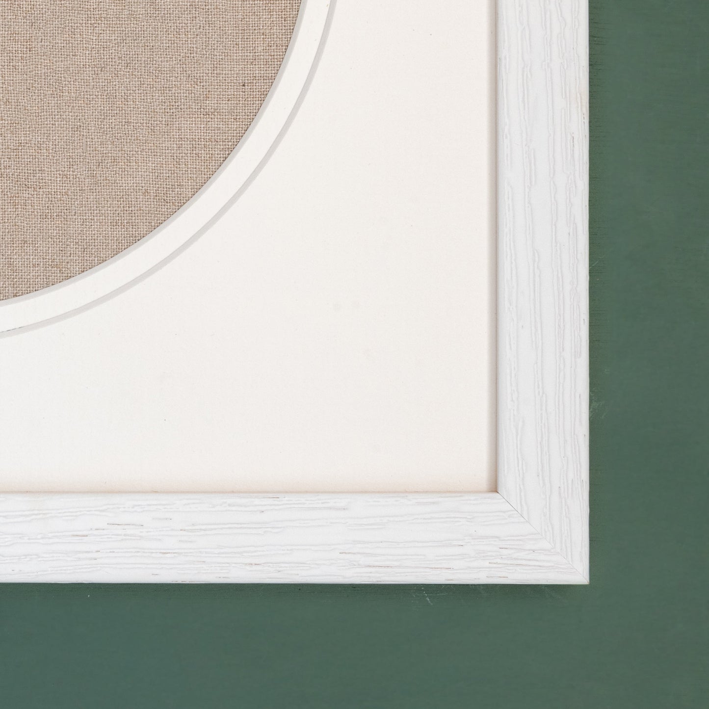 A close up showing the detail of the top right hand corner of a white frame and circular double mount.