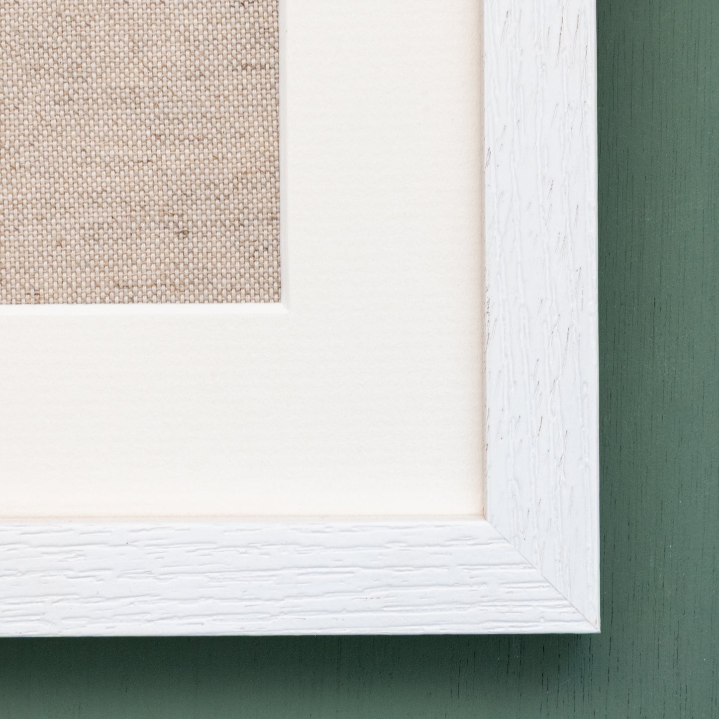 A close up showing the detail of the bottom right hand corner of a white frame and mount.