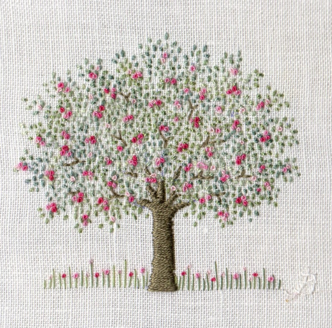 Simple hand embroidered apple tree with pink blossom on a white linen background
