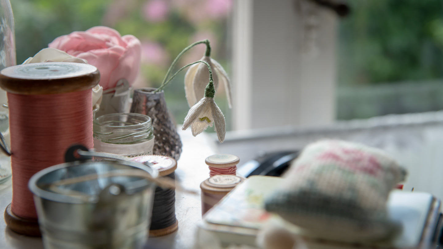 Stump work snowdrops staged amongst cotton reels and other accessories