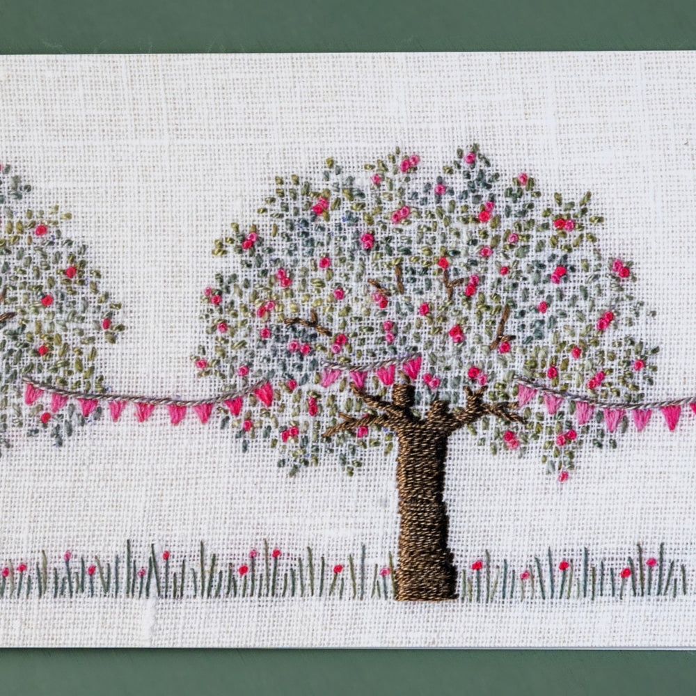An apple tree with pink Blossom is draped in pretty matching pink bunting.