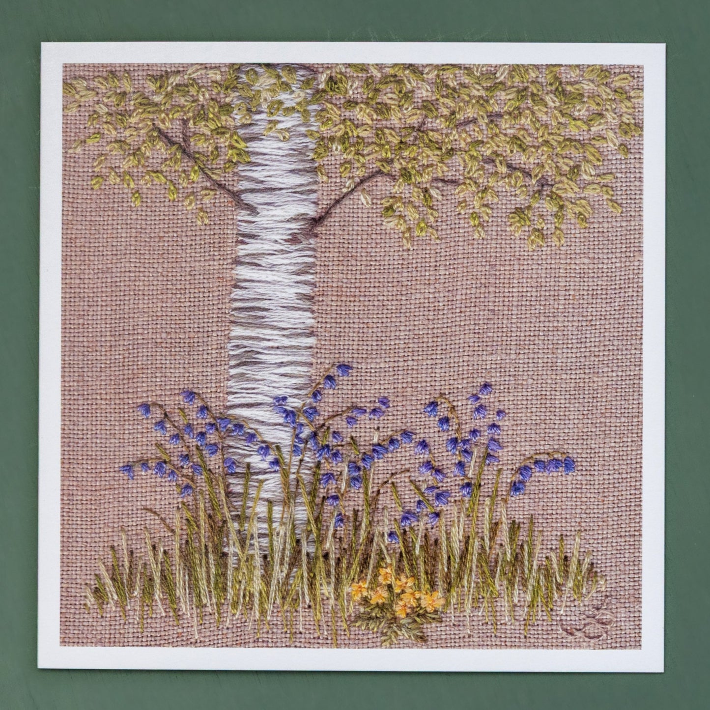A card of a hand embroidered silver birch tree trunk and the lower branches 