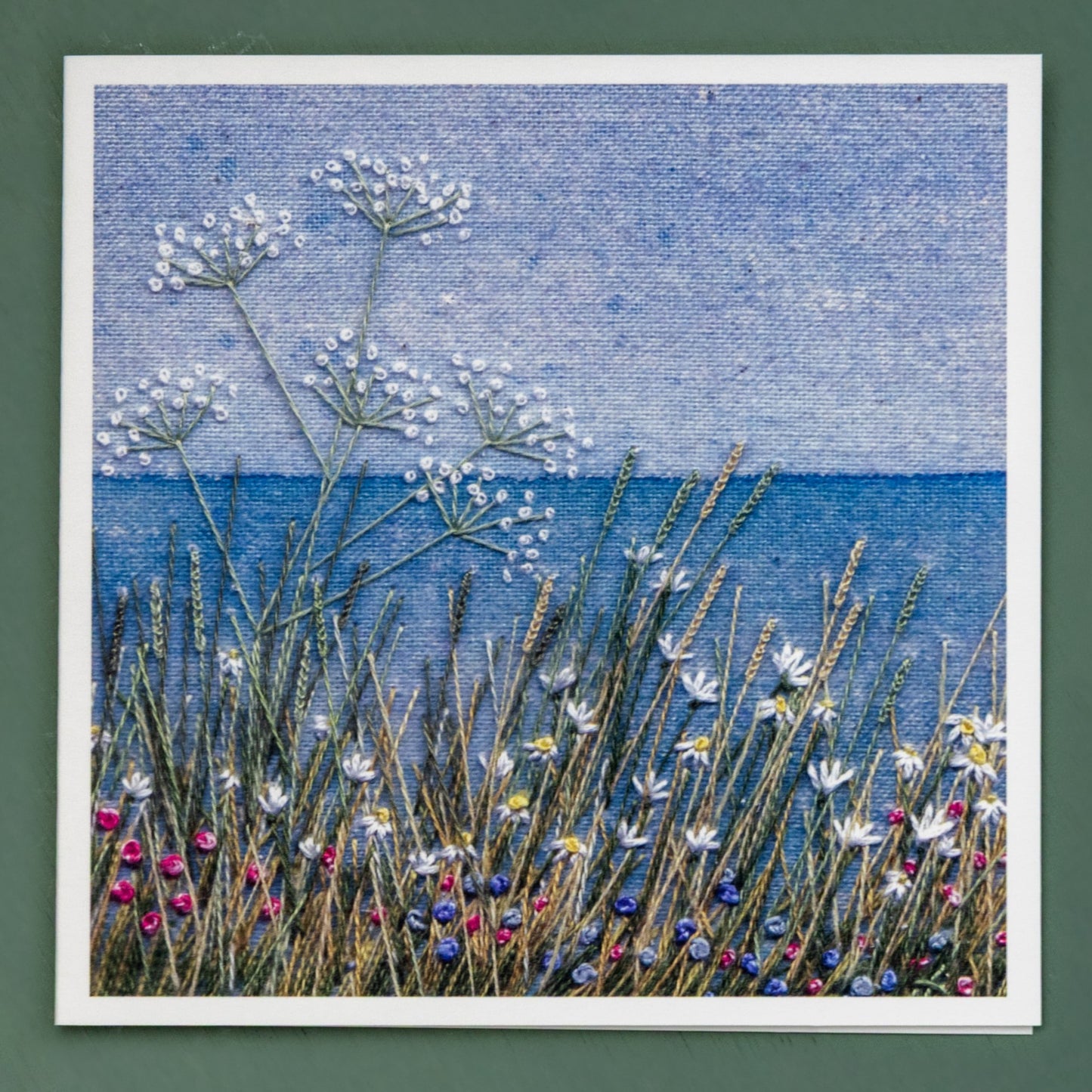 A painted coasted horizon with a flower meadow in the foreground. 