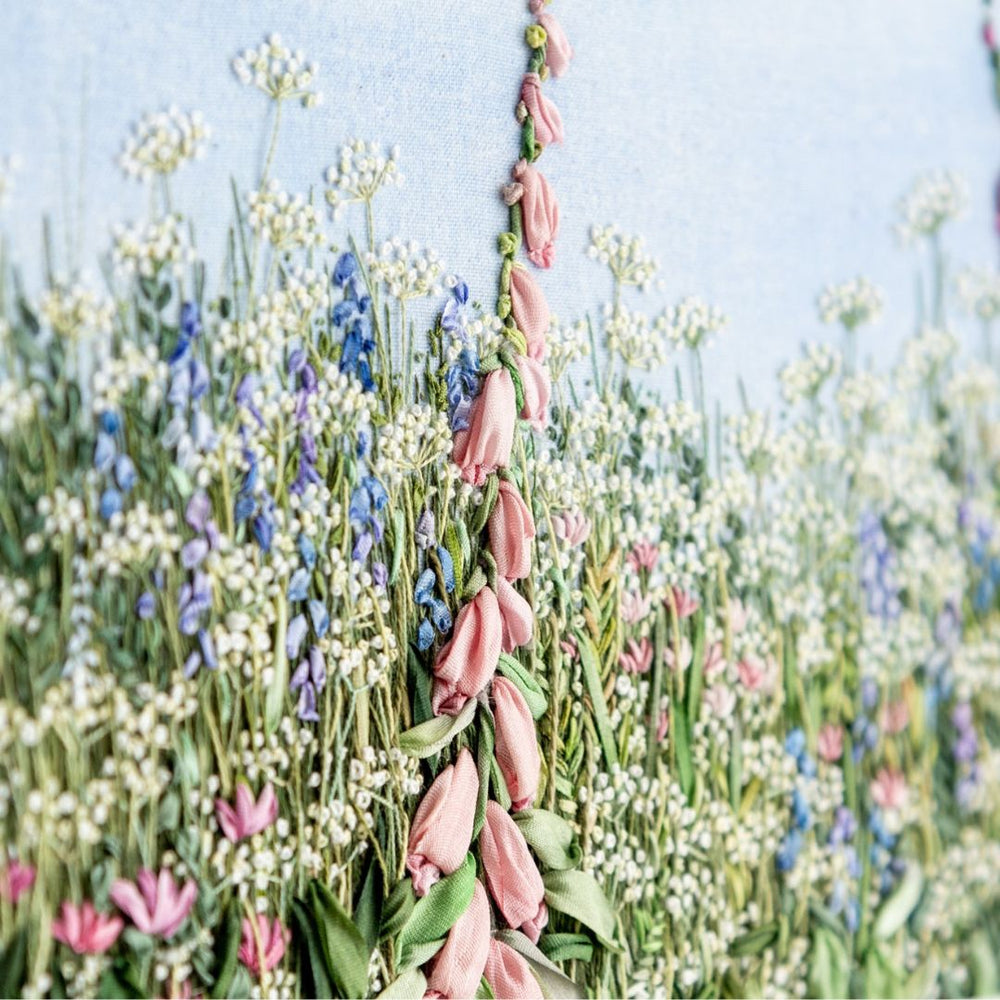 close up of a pink foxglove spire amongst the cow parsley and other meadow flowers